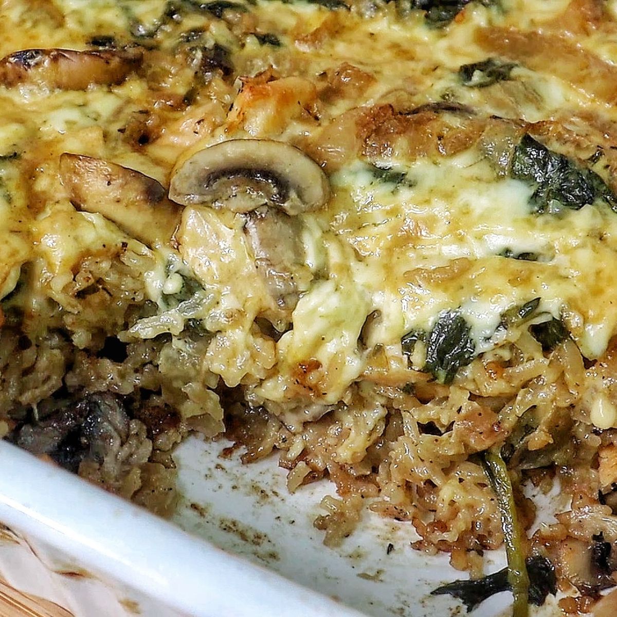 French Onion Chicken and Rice casserole with melted cheese, mushrooms, spinach, and tender chicken pieces baked together in a creamy rice mixture.