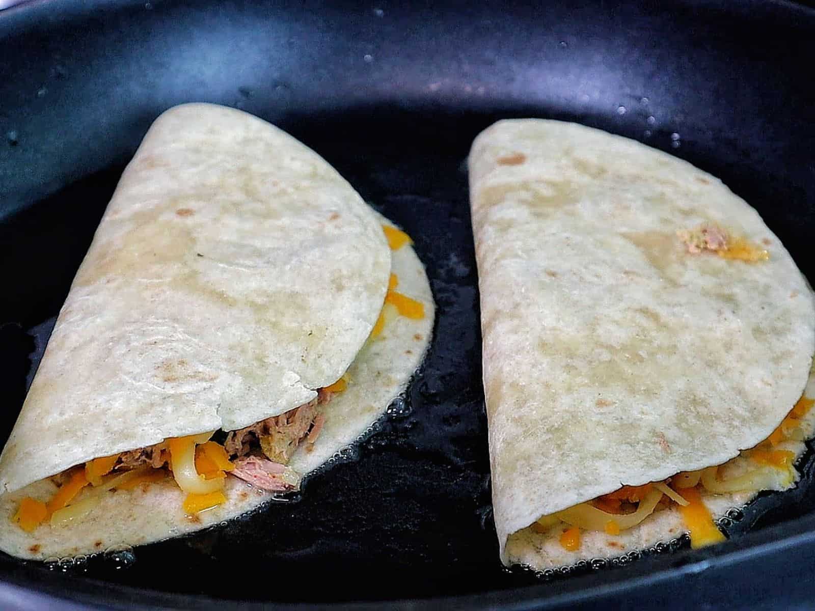 Golden brown tuna melt quesadilla, filled with melted cheese, tuna, and onions.
