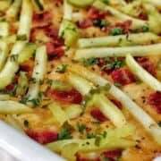 A golden-baked bacon cheeseburger casserole topped with melted cheese, crispy bacon pieces, pickle slices, and fresh parsley