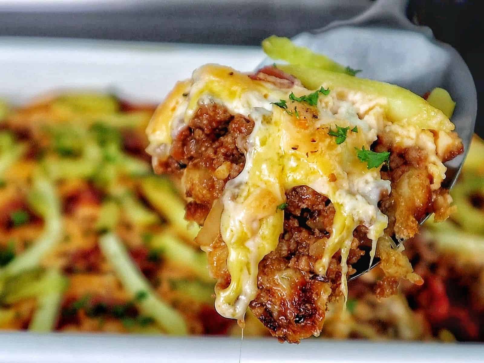 A golden-baked bacon cheeseburger casserole topped with melted cheese, crispy bacon pieces, pickle slices, and fresh parsley