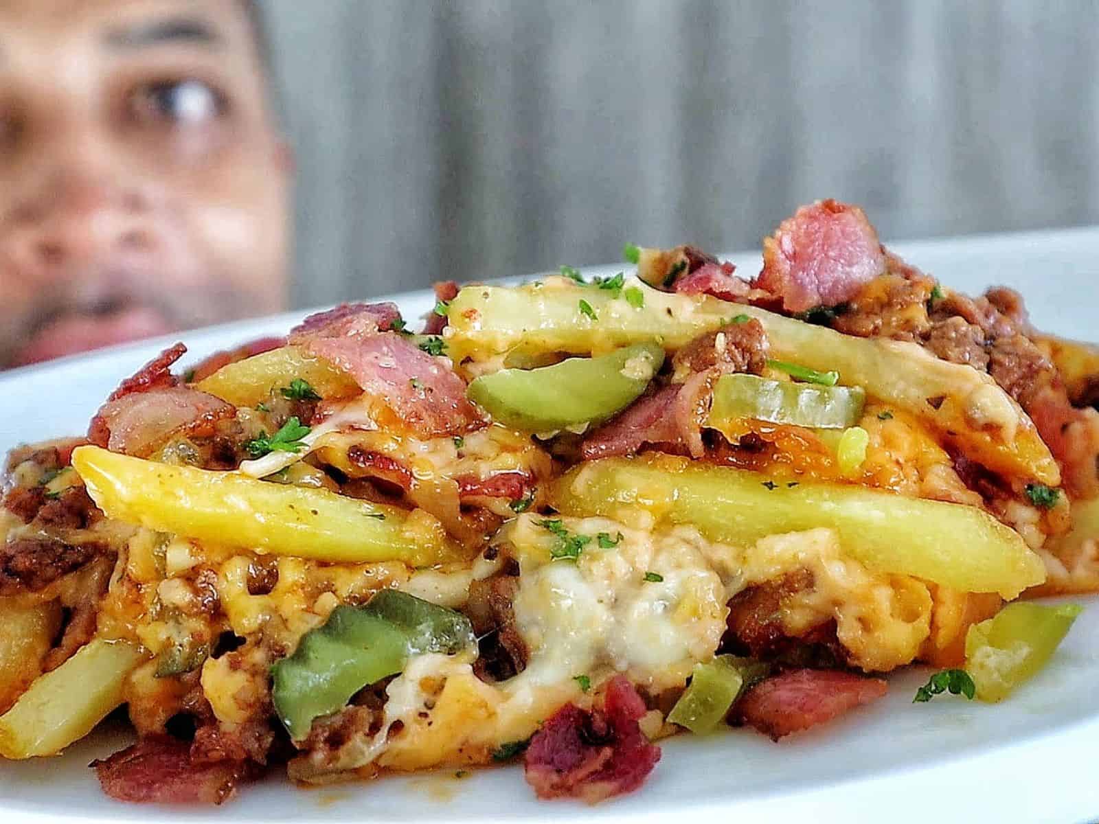 A golden-baked bacon cheeseburger casserole topped with melted cheese, crispy bacon pieces, pickle slices, and fresh parsley
