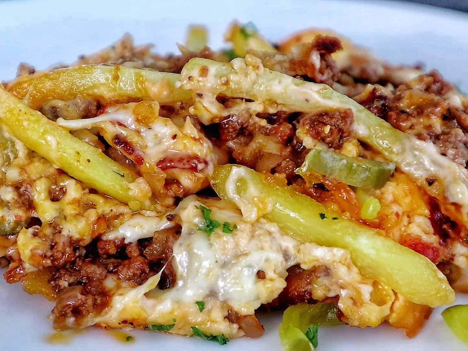 A golden-baked bacon cheeseburger casserole topped with melted cheese, crispy bacon pieces, pickle slices, and fresh parsley