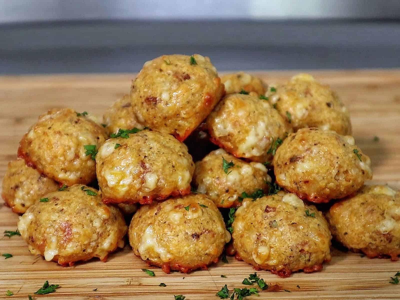 Cheesy Parmesan Mozzarella Bacon Bites stacked on a wooden board, garnished with fresh parsley, showcasing a cheesy, crispy texture.