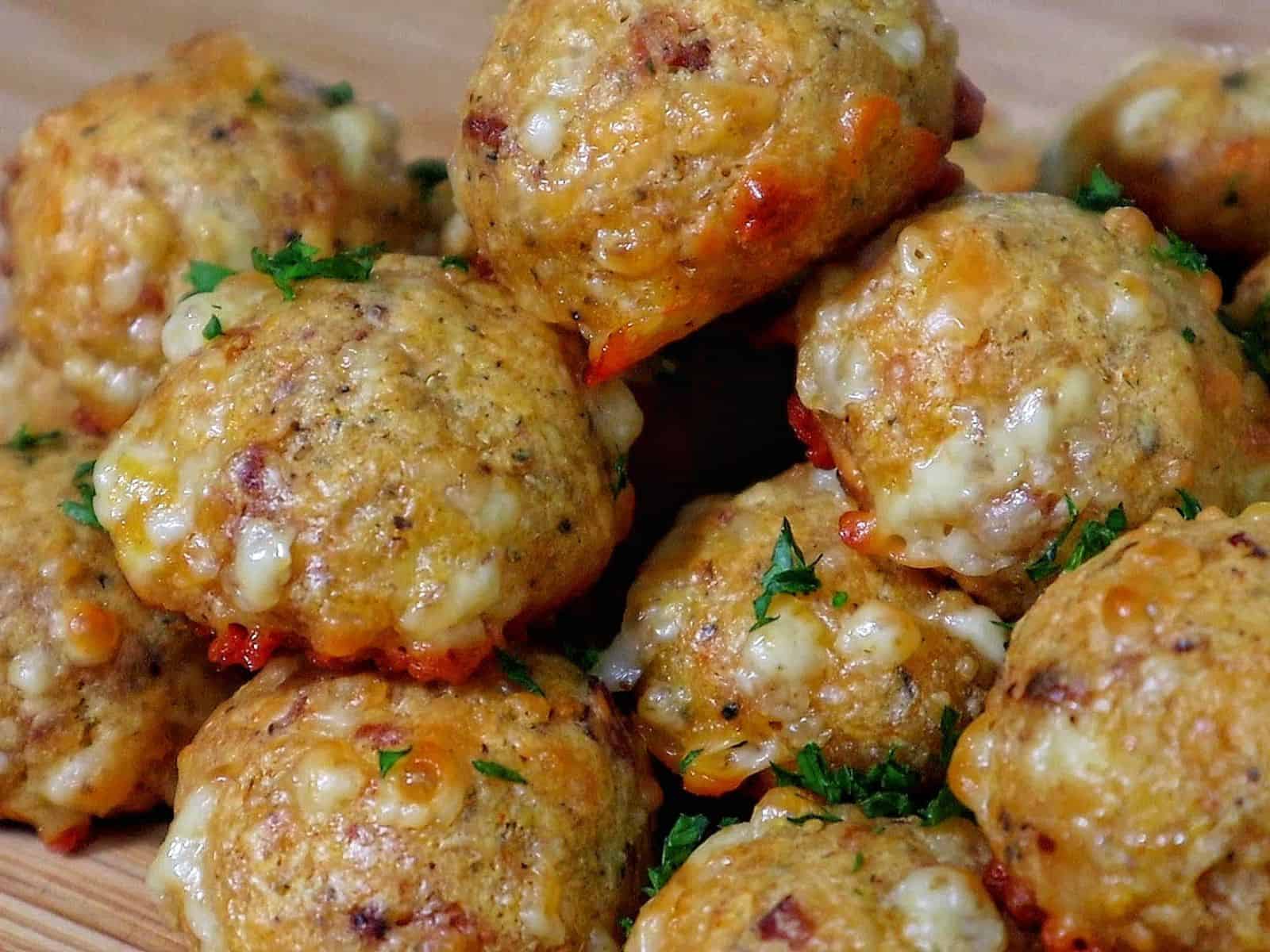 Cheesy Parmesan Mozzarella Bacon Bites stacked on a wooden board, garnished with fresh parsley, showcasing a cheesy, crispy texture.
