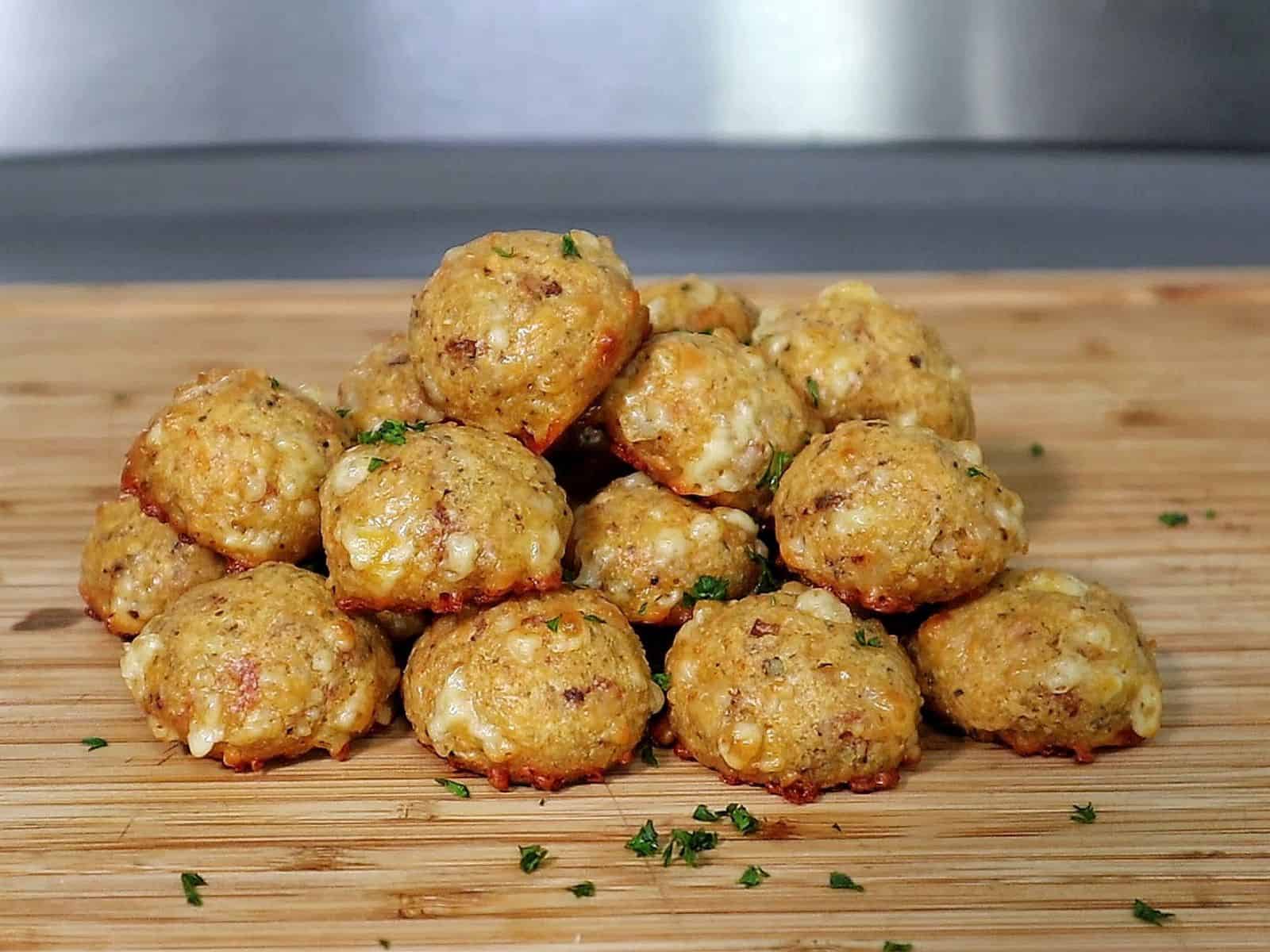 Cheesy Parmesan Mozzarella Bacon Bites stacked on a wooden board, garnished with fresh parsley, showcasing a cheesy, crispy texture.