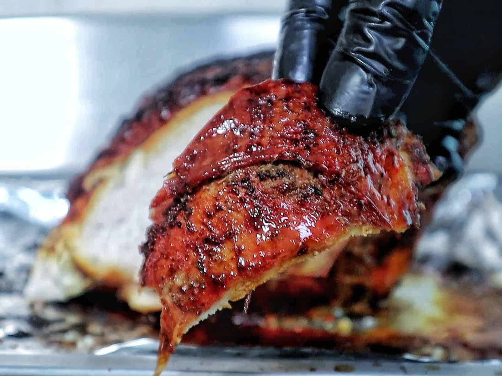 A golden brown air fryer turkey breast seasoned with a dark caramelized crust and juices pooling at the bottom.