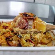 Cheesy sausage and potato casserole, featuring golden melted cheese, browned sausage slices, and tender potato cubes scooped from a baking dish.