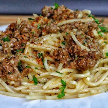 Creamy Cajun beef spaghetti, featuring tender spaghetti noodles coated in a rich, cheesy sauce with seasoned ground beef and sprinkled with fresh parsley.