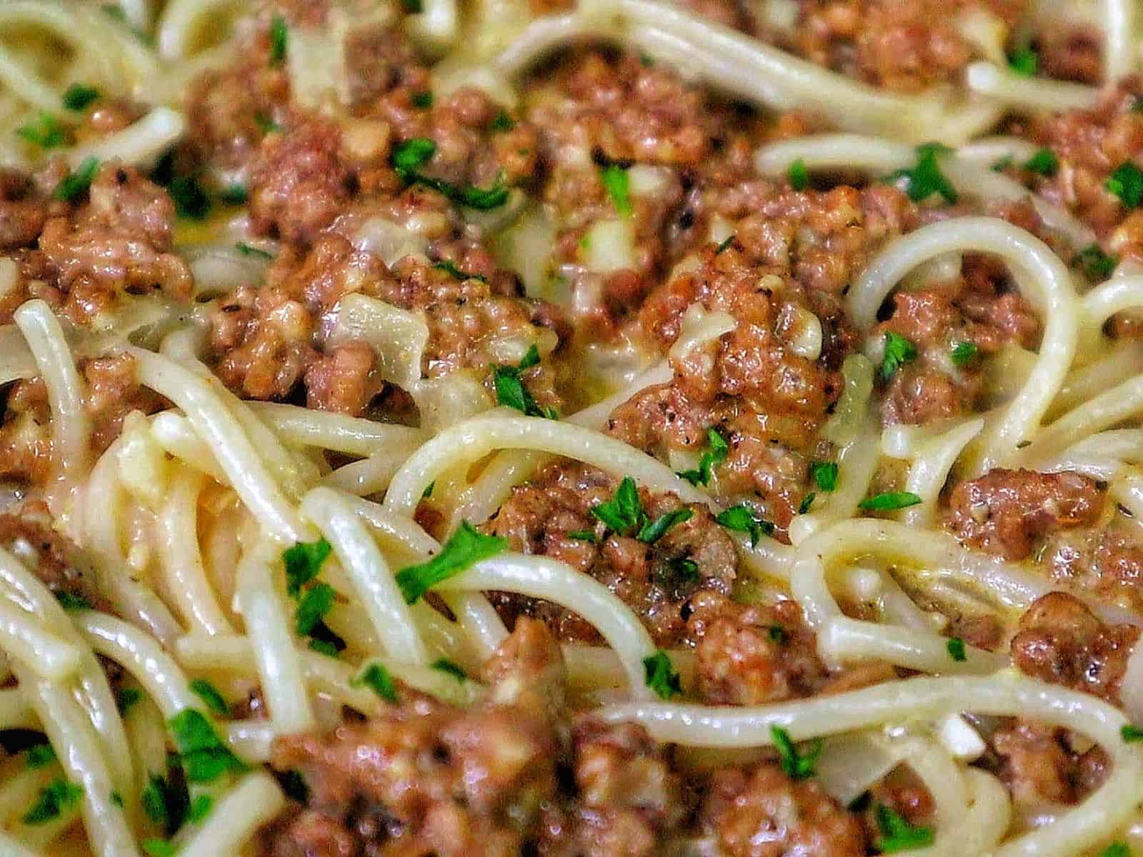Creamy Cajun beef spaghetti, featuring tender spaghetti noodles coated in a rich, cheesy sauce with seasoned ground beef and sprinkled with fresh parsley.