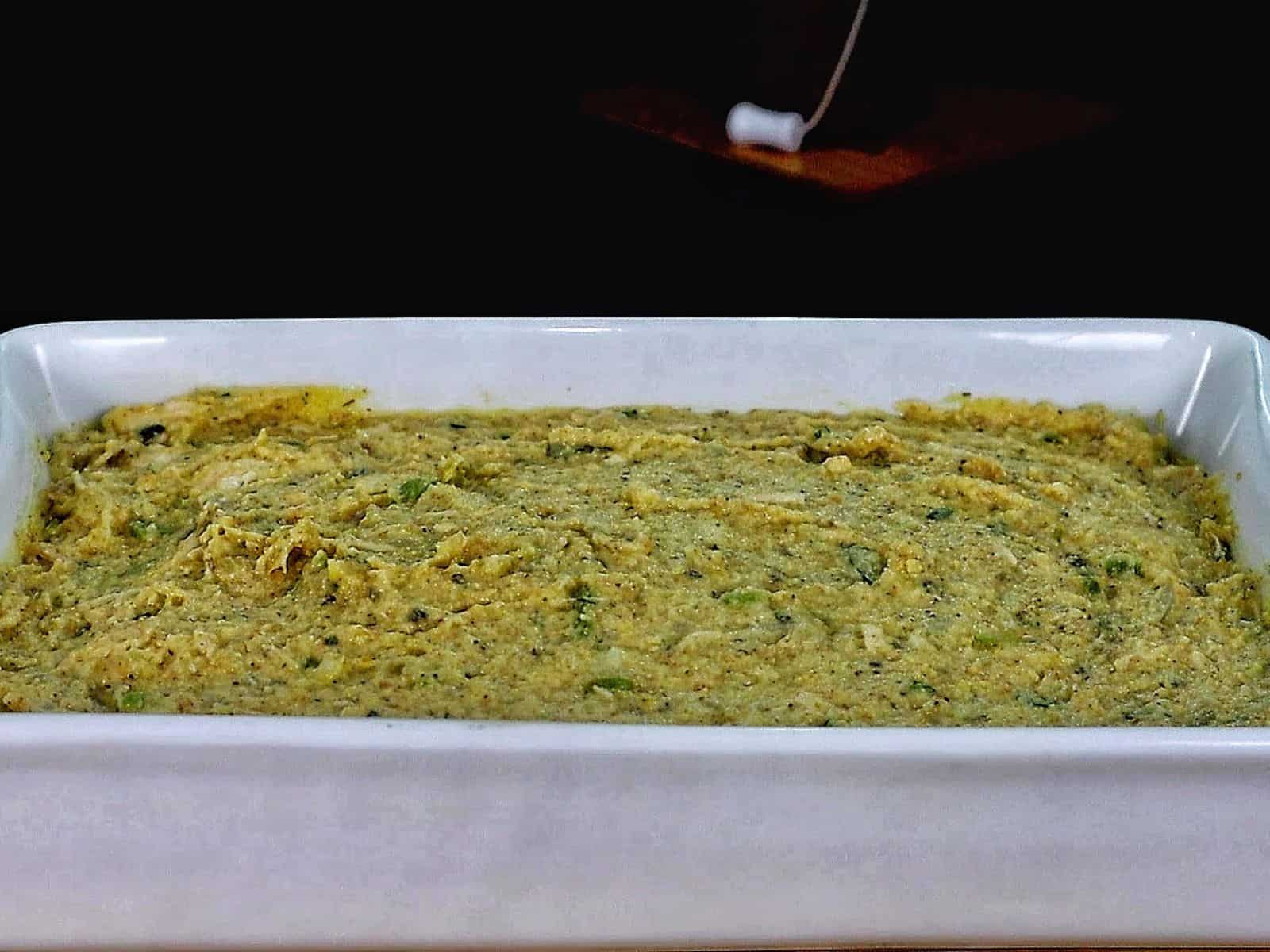 Golden Southern cornbread dressing topped with rich brown gravy, showing tender chunks of shredded chicken and herbs.