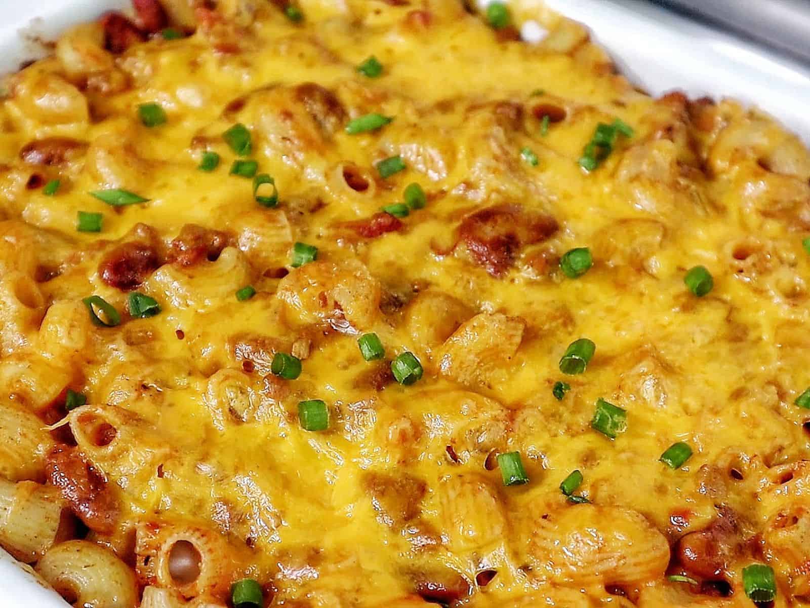 Cheesy chili mac casserole baked until bubbly and golden, made with elbow macaroni, ground beef, kidney beans, and melted cheddar cheese, garnished with green onions.