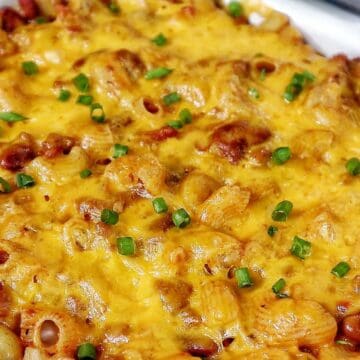 Cheesy chili mac casserole baked until bubbly and golden, made with elbow macaroni, ground beef, kidney beans, and melted cheddar cheese, garnished with green onions.