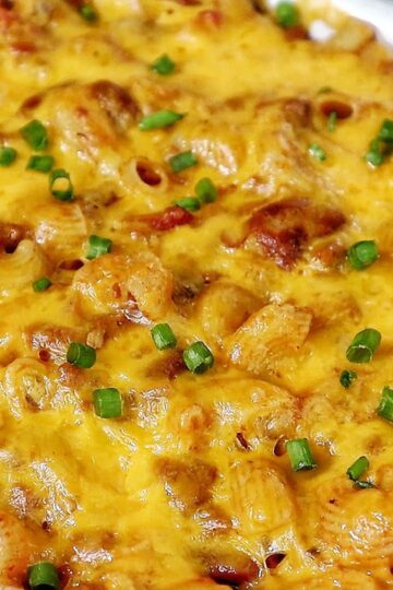 Cheesy chili mac casserole baked until bubbly and golden, made with elbow macaroni, ground beef, kidney beans, and melted cheddar cheese, garnished with green onions.