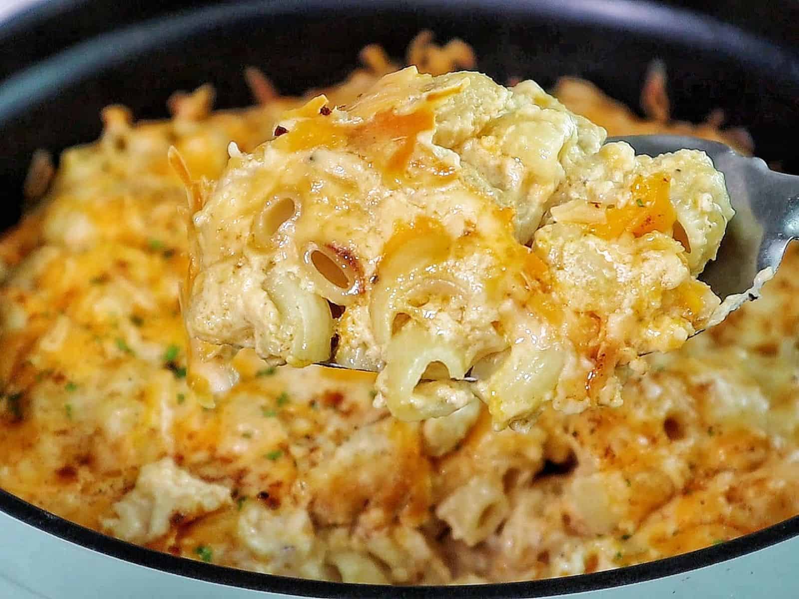 Creamy slow cooker mac and cheese topped with melted cheddar and herbs, showing tender elbow noodles coated in a rich, golden cheese sauce.