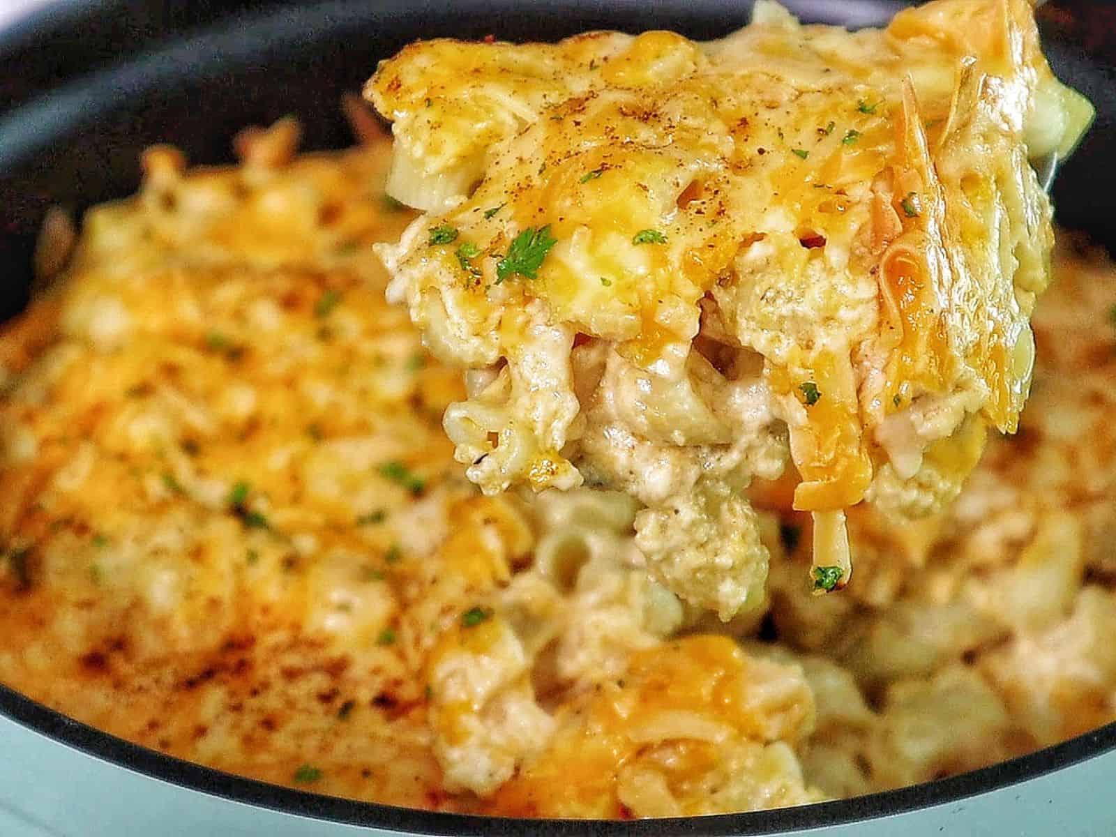 Creamy slow cooker mac and cheese topped with melted cheddar and herbs, showing tender elbow noodles coated in a rich, golden cheese sauce.