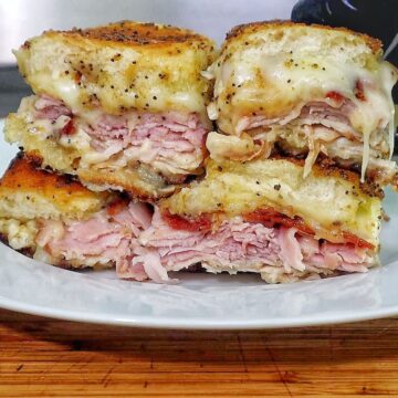 Golden baked Hawaiian roll sliders layered with turkey, ham, crispy bacon, and melted provolone, brushed with garlic butter.