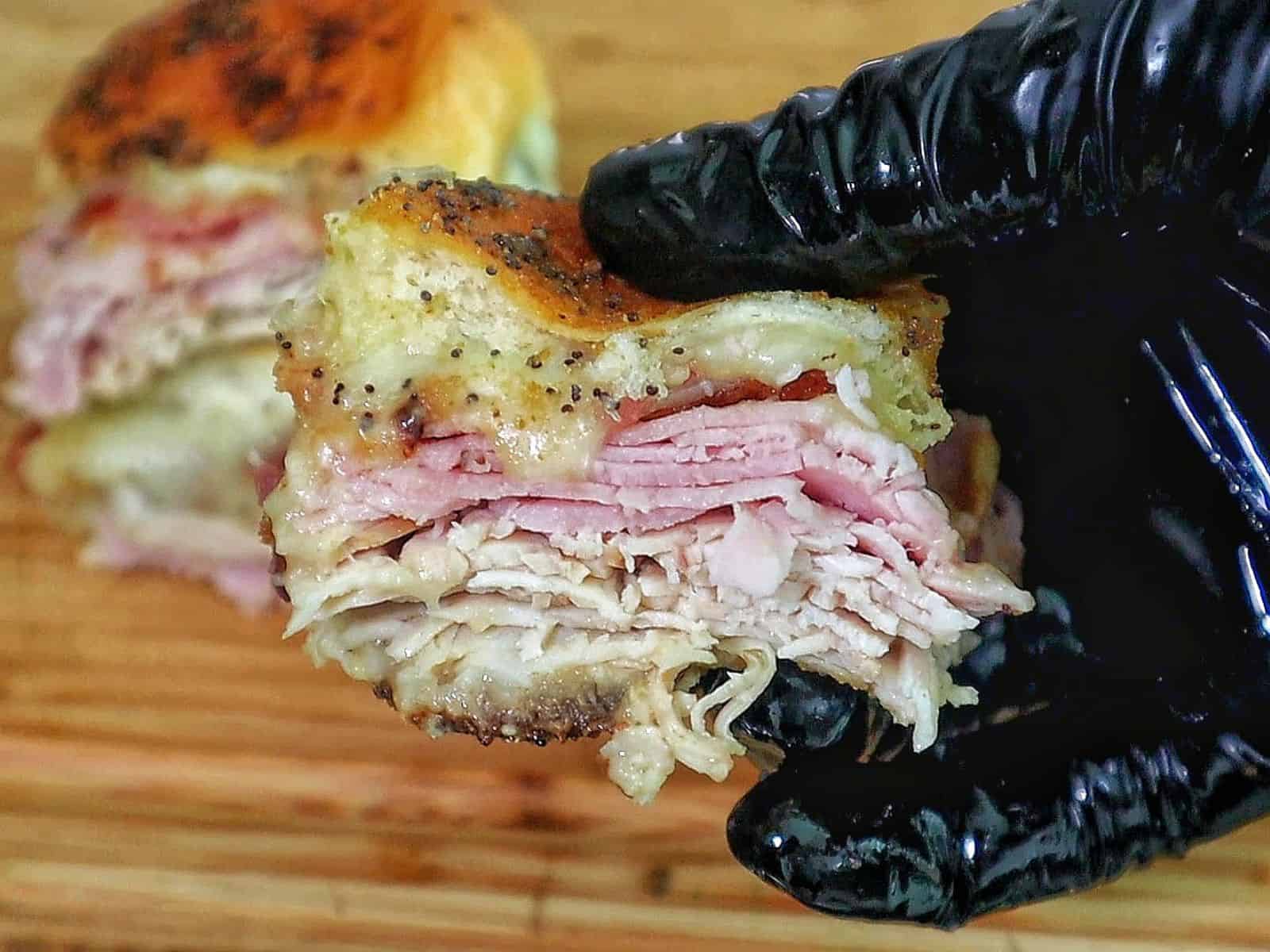 Golden baked Hawaiian roll sliders layered with turkey, ham, crispy bacon, and melted provolone, brushed with garlic butter.