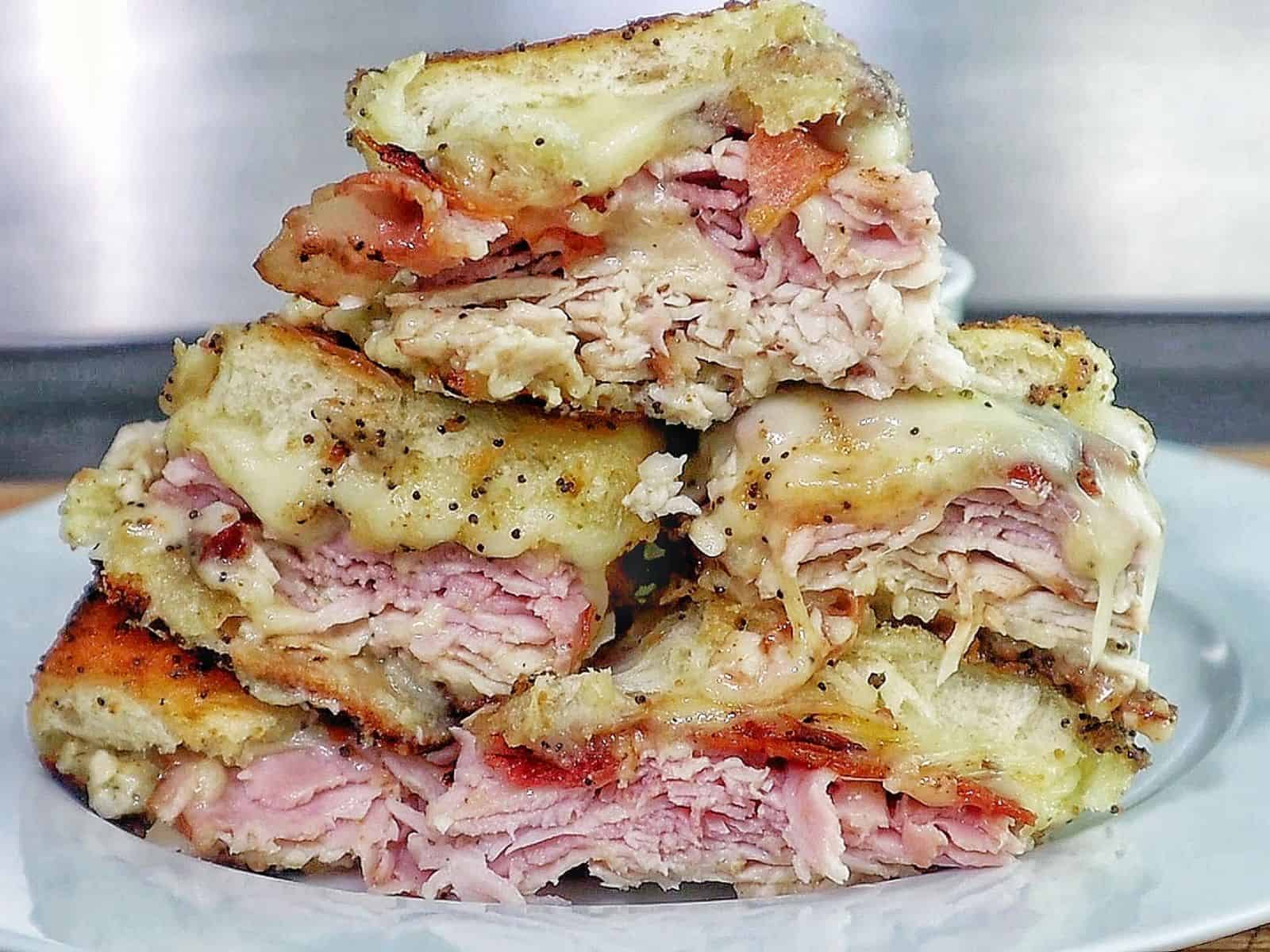Golden baked Hawaiian roll sliders layered with turkey, ham, crispy bacon, and melted provolone, brushed with garlic butter.