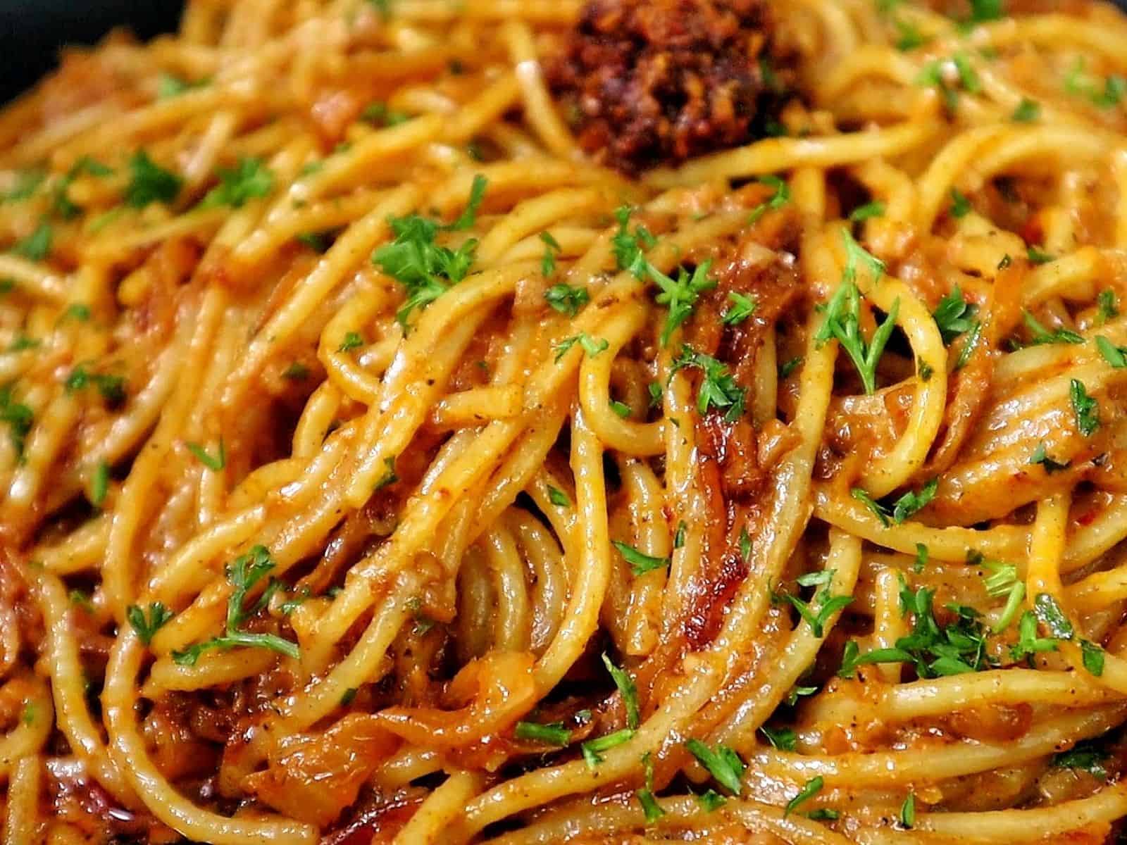 Caramelized onion and garlic spaghetti tossed in a savory sauce garnished with fresh parsley and chili crisp.