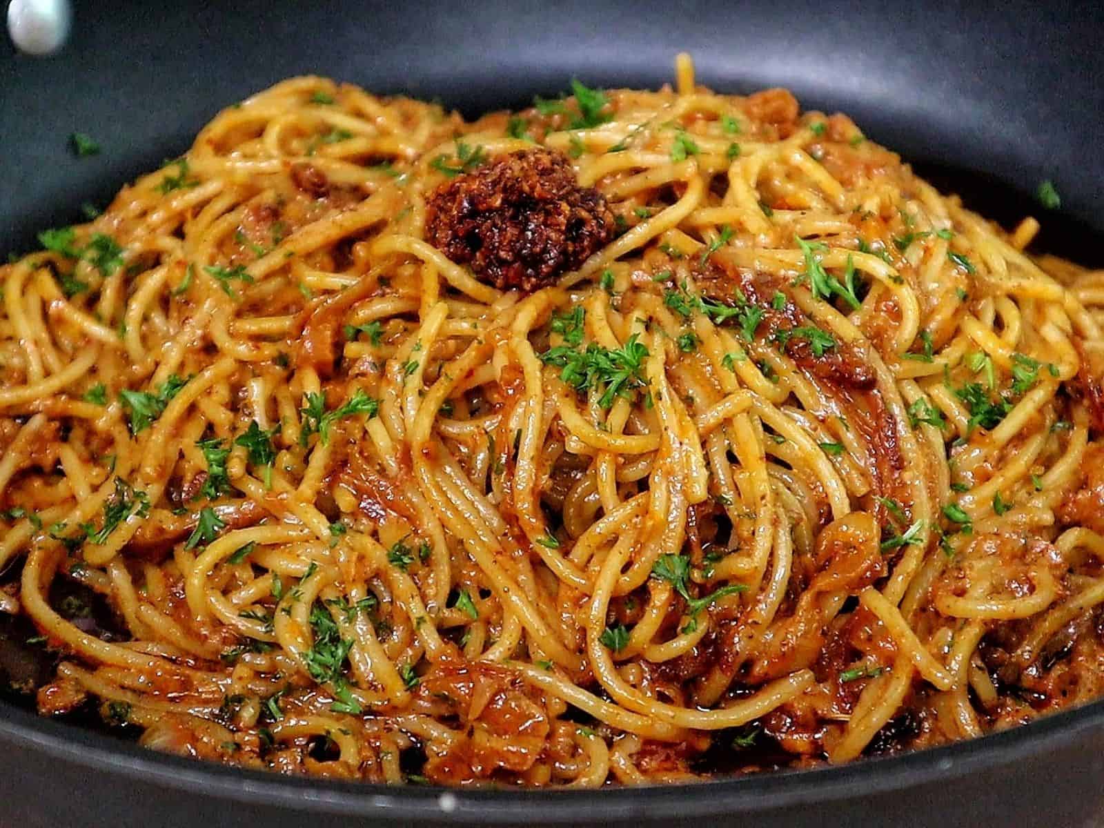 Caramelized onion and garlic spaghetti tossed in a savory sauce garnished with fresh parsley and chili crisp.