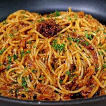 Caramelized onion and garlic spaghetti tossed in a savory sauce garnished with fresh parsley and chili crisp.