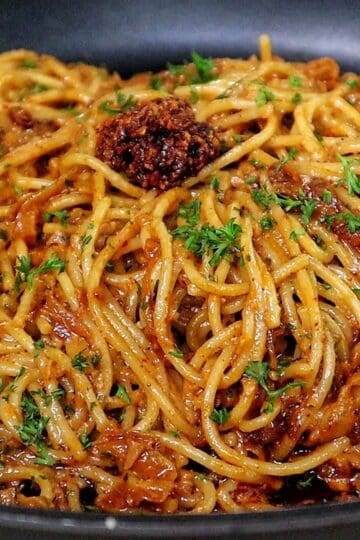 Caramelized onion and garlic spaghetti tossed in a savory sauce garnished with fresh parsley and chili crisp.