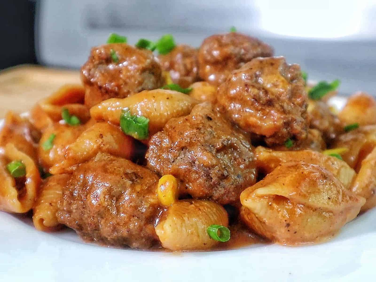 Cheddar BBQ ranch meatball pasta in a skillet with shell pasta, tender meatballs, creamy BBQ ranch sauce, melted cheddar cheese, sweet corn, and green onion garnish.