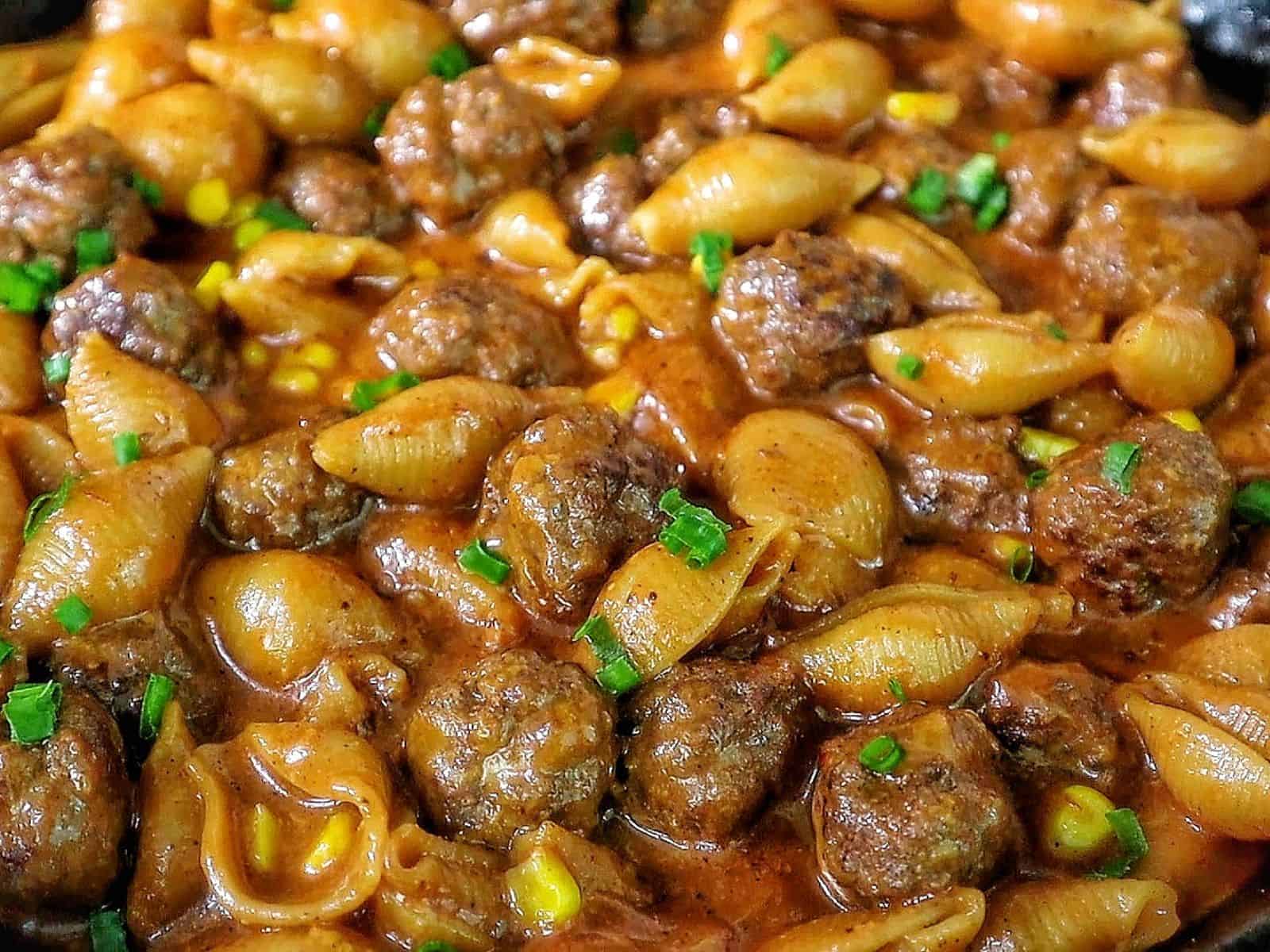 Cheddar BBQ ranch meatball pasta in a skillet with shell pasta, tender meatballs, creamy BBQ ranch sauce, melted cheddar cheese, sweet corn, and green onion garnish.