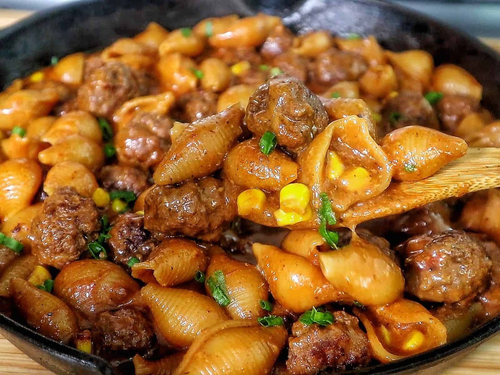 Cheddar BBQ ranch meatball pasta in a skillet with shell pasta, tender meatballs, creamy BBQ ranch sauce, melted cheddar cheese, sweet corn, and green onion garnish.