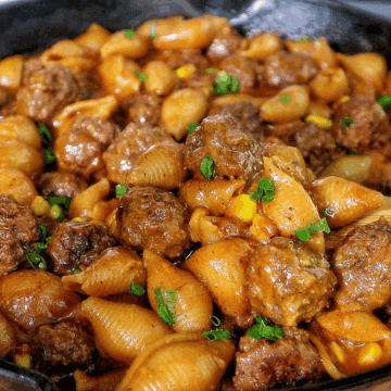 Cheddar BBQ ranch meatball pasta in a skillet with shell pasta, tender meatballs, creamy BBQ ranch sauce, melted cheddar cheese, sweet corn, and green onion garnish.