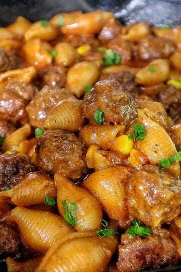Cheddar BBQ ranch meatball pasta in a skillet with shell pasta, tender meatballs, creamy BBQ ranch sauce, melted cheddar cheese, sweet corn, and green onion garnish.