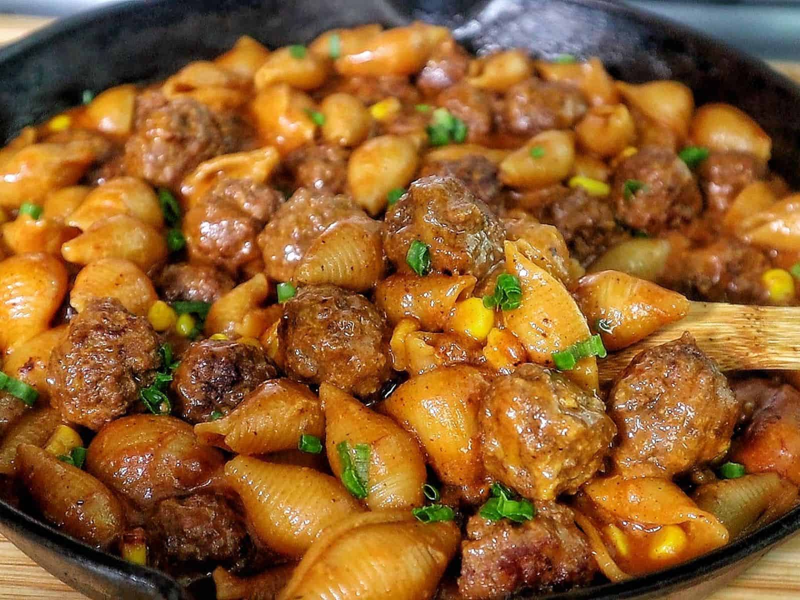 Cheddar BBQ ranch meatball pasta in a skillet with shell pasta, tender meatballs, creamy BBQ ranch sauce, melted cheddar cheese, sweet corn, and green onion garnish.