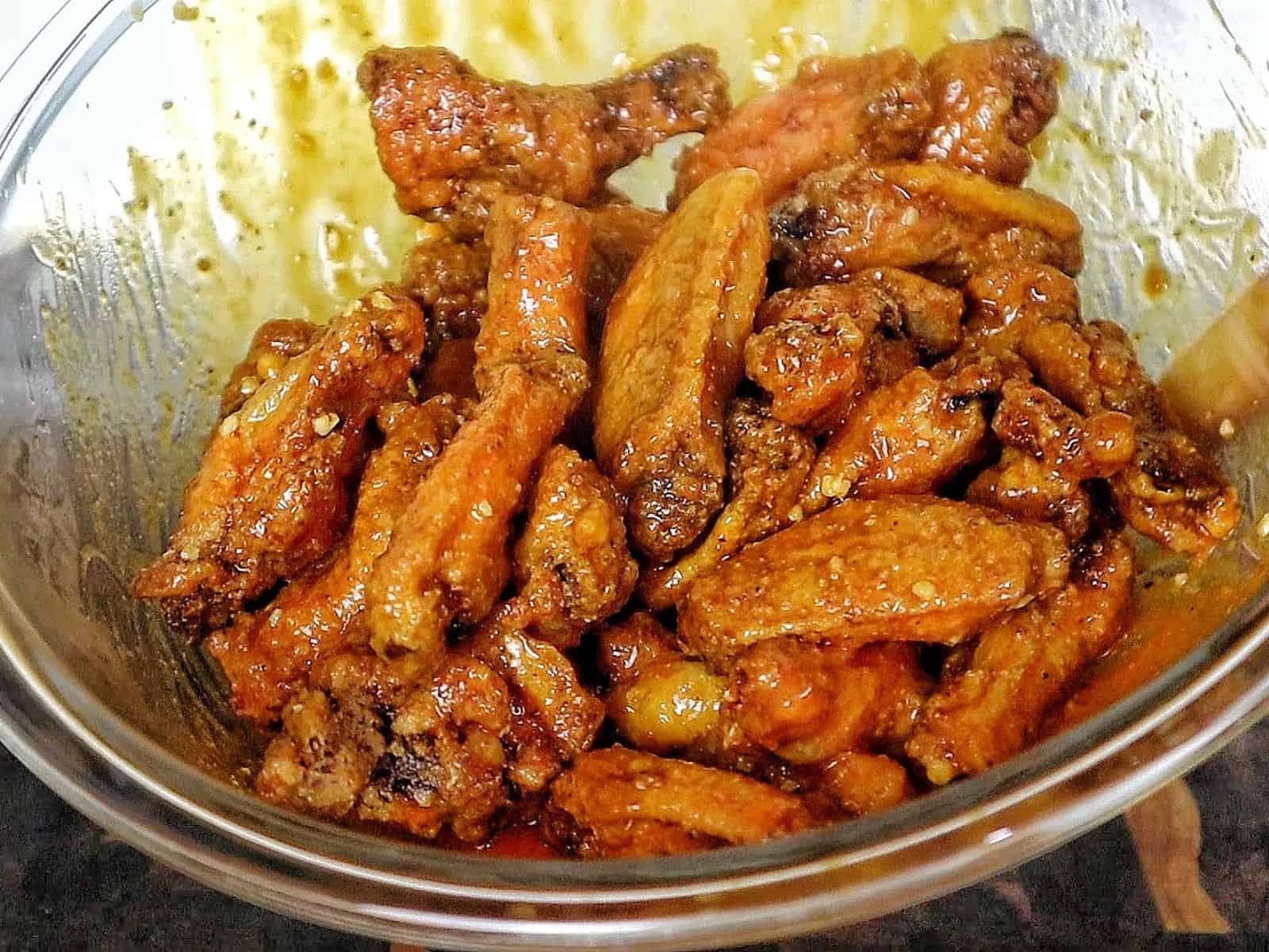 Crispy buffalo chicken wings tossed in a homemade buffalo sauce and garnished with green onions on a white plate.