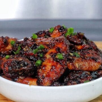 Air fryer honey chipotle chicken wings coated in a sticky sauce, garnished with chopped green onions.