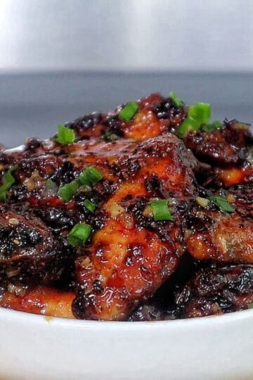 Air fryer honey chipotle chicken wings coated in a sticky sauce, garnished with chopped green onions.