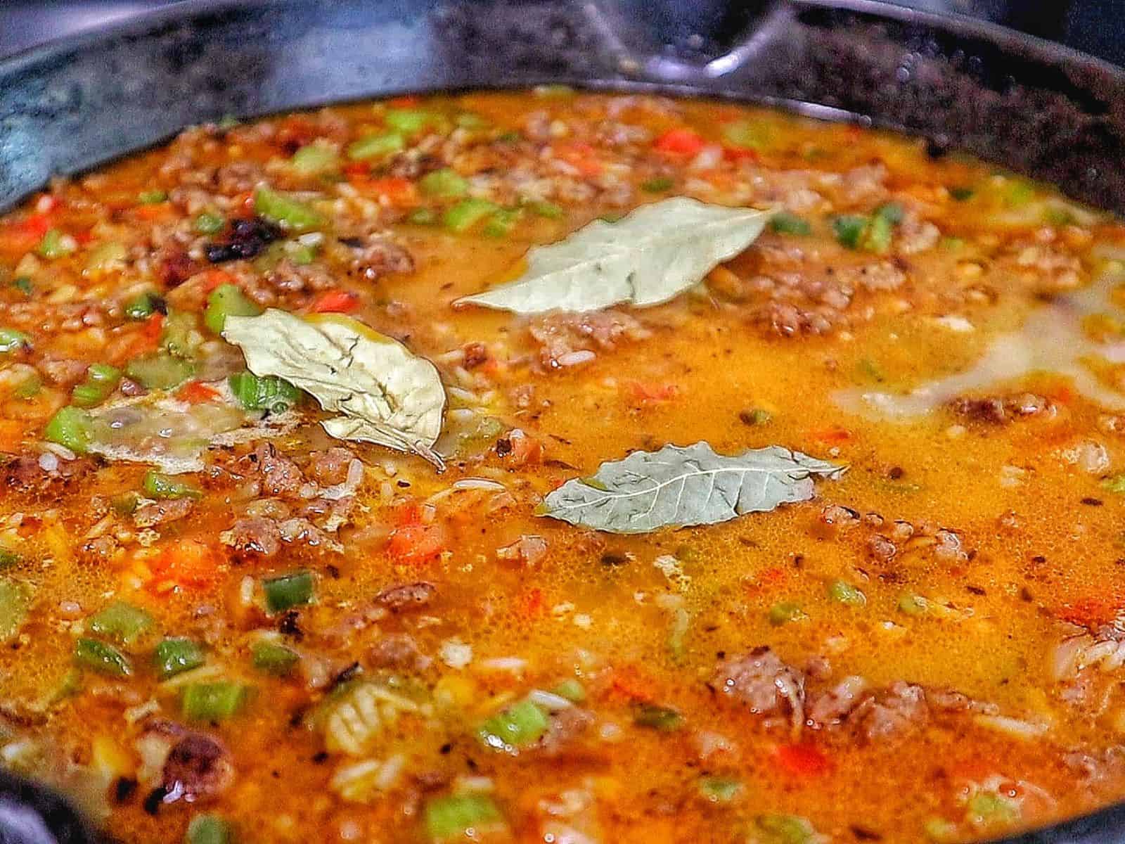 Pappadeaux dirty rice made with seasoned sausage, fluffy long-grain rice, diced bell peppers, celery, and onions, cooked in a cast iron skillet and garnished with fresh parsley.