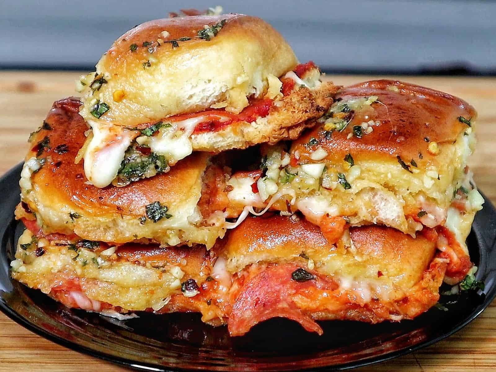 Pull-apart pizza sliders made with Hawaiian rolls, layered with melted mozzarella, pepperoni, pizza sauce, and brushed with a garlic herb butter topping. 