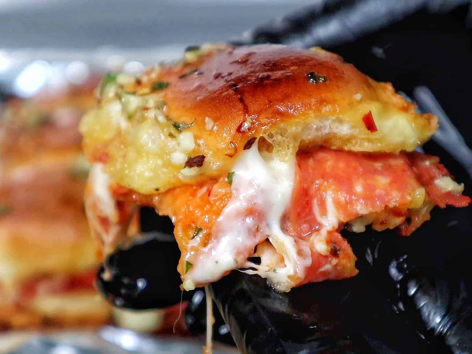 Pull-apart pizza sliders made with Hawaiian rolls, layered with melted mozzarella, pepperoni, pizza sauce, and brushed with a garlic herb butter topping.