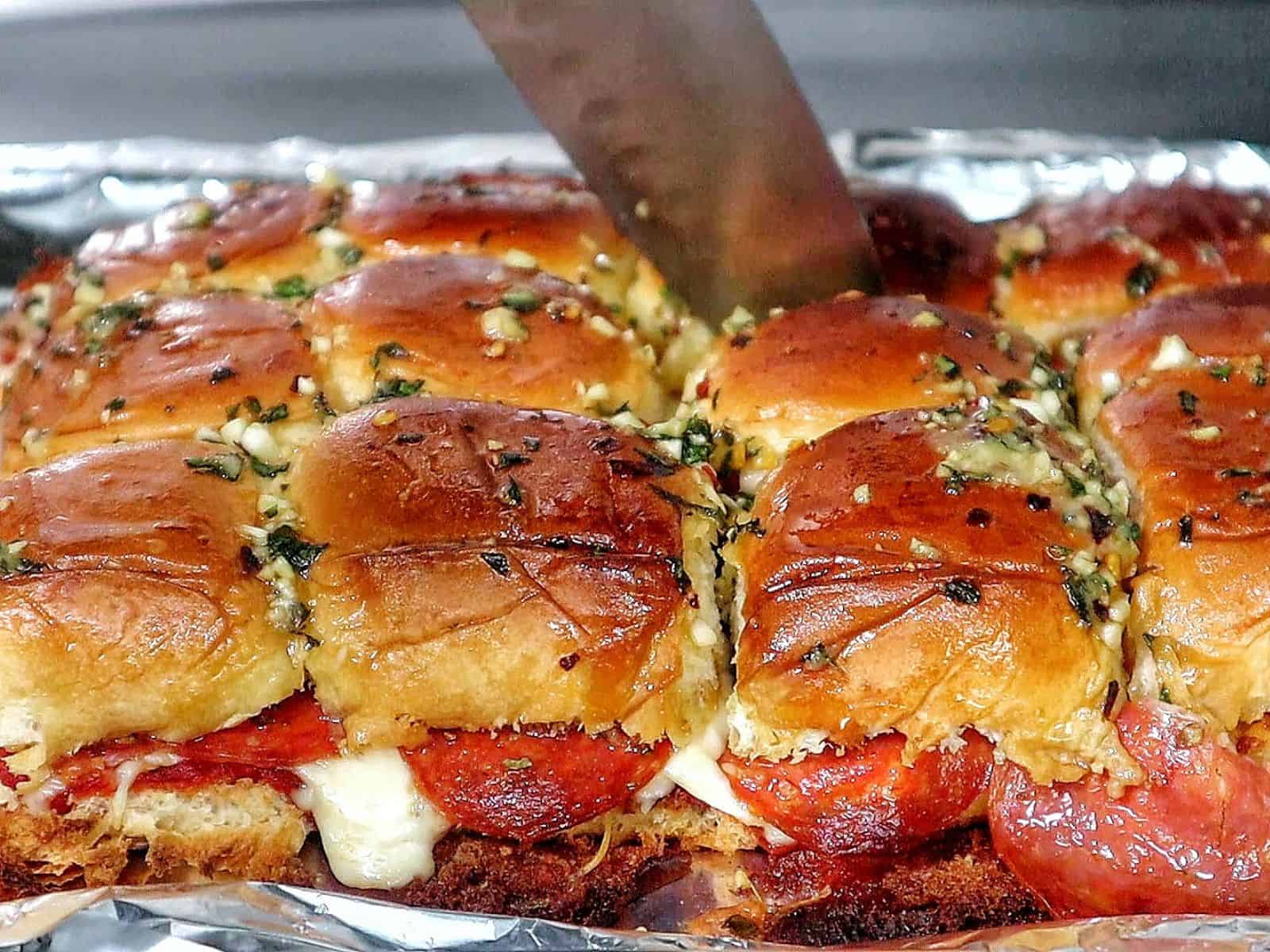 Pull-apart pizza sliders made with Hawaiian rolls, layered with melted mozzarella, pepperoni, pizza sauce, and brushed with a garlic herb butter topping.