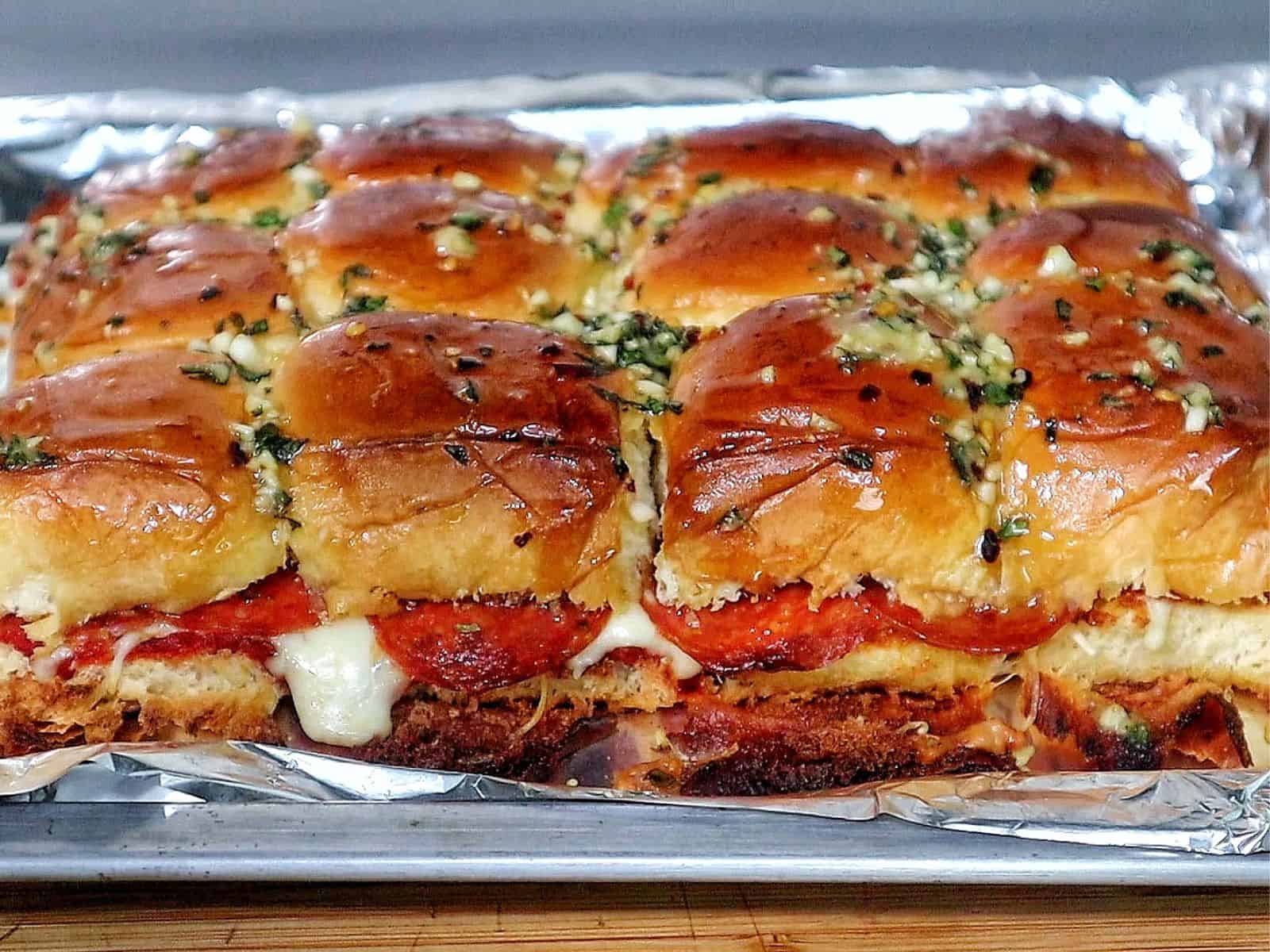 Pull-apart pizza sliders made with Hawaiian rolls, layered with melted mozzarella, pepperoni, pizza sauce, and brushed with a garlic herb butter topping.
