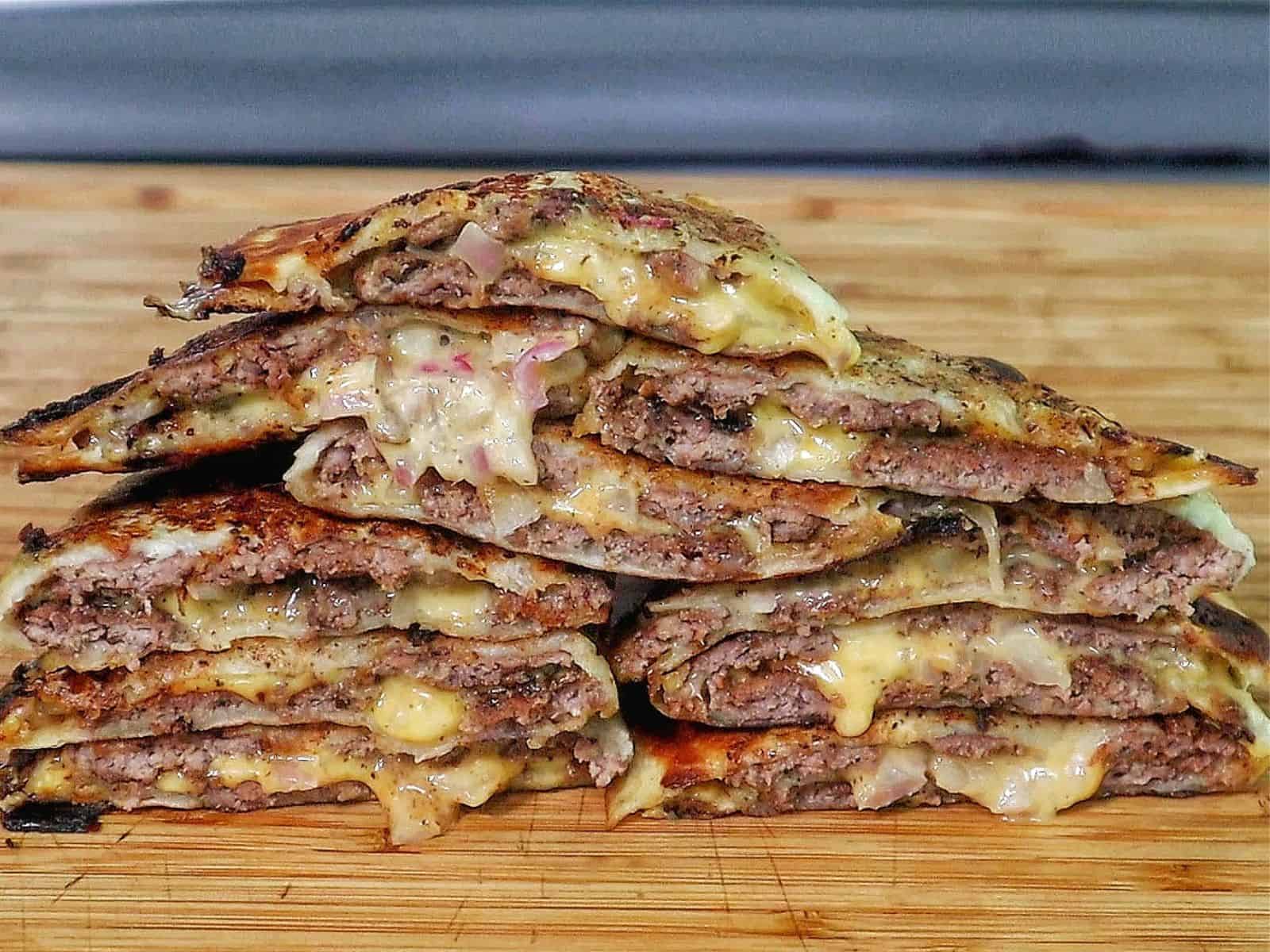 Smashburger quesadillas filled with seasoned ground beef, melted American cheese, diced onions, in a crispy toasted tortilla.