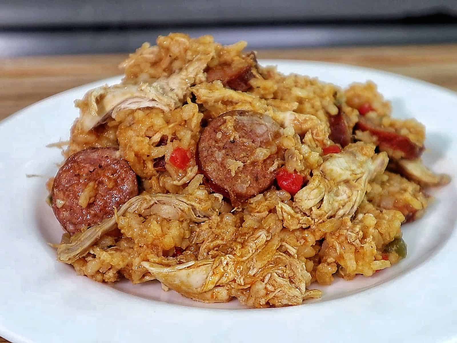 Southern Chicken Bog served on a white plate, featuring tender shredded chicken, sliced andouille sausage, and seasoned rice with bell peppers.
