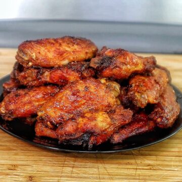 Crispy air-fried spicy blackened chicken wings coated in a buttery hot sauce glaze, served fresh and ready to eat.