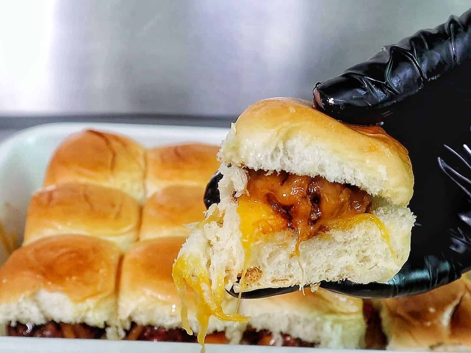 cheesy sweet and spicy BBQ meatball sliders baked inside soft Hawaiian rolls, topped with melted cheddar