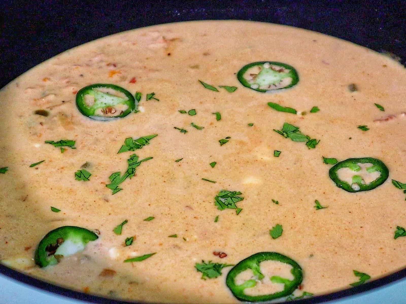 Creamy jalapeño popper chicken soup topped with fresh sliced jalapeños, crispy bacon, and chopped cilantro.