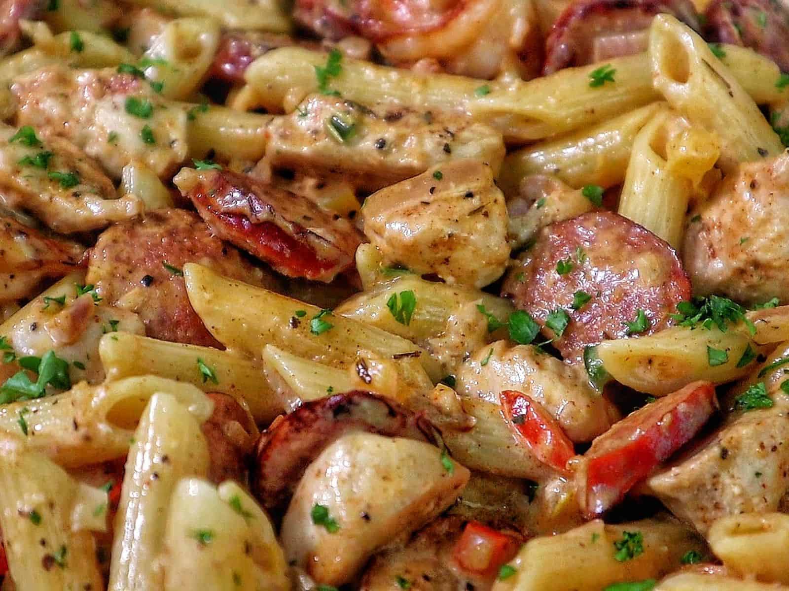 Creamy Cajun penne pasta with shrimp, sliced andouille sausage, and chunks of chicken, tossed in a rich Parmesan cream sauce and garnished with fresh parsley.