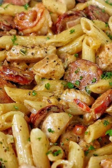 Creamy Cajun penne pasta with shrimp, sliced andouille sausage, and chunks of chicken, tossed in a rich Parmesan cream sauce and garnished with fresh parsley.
