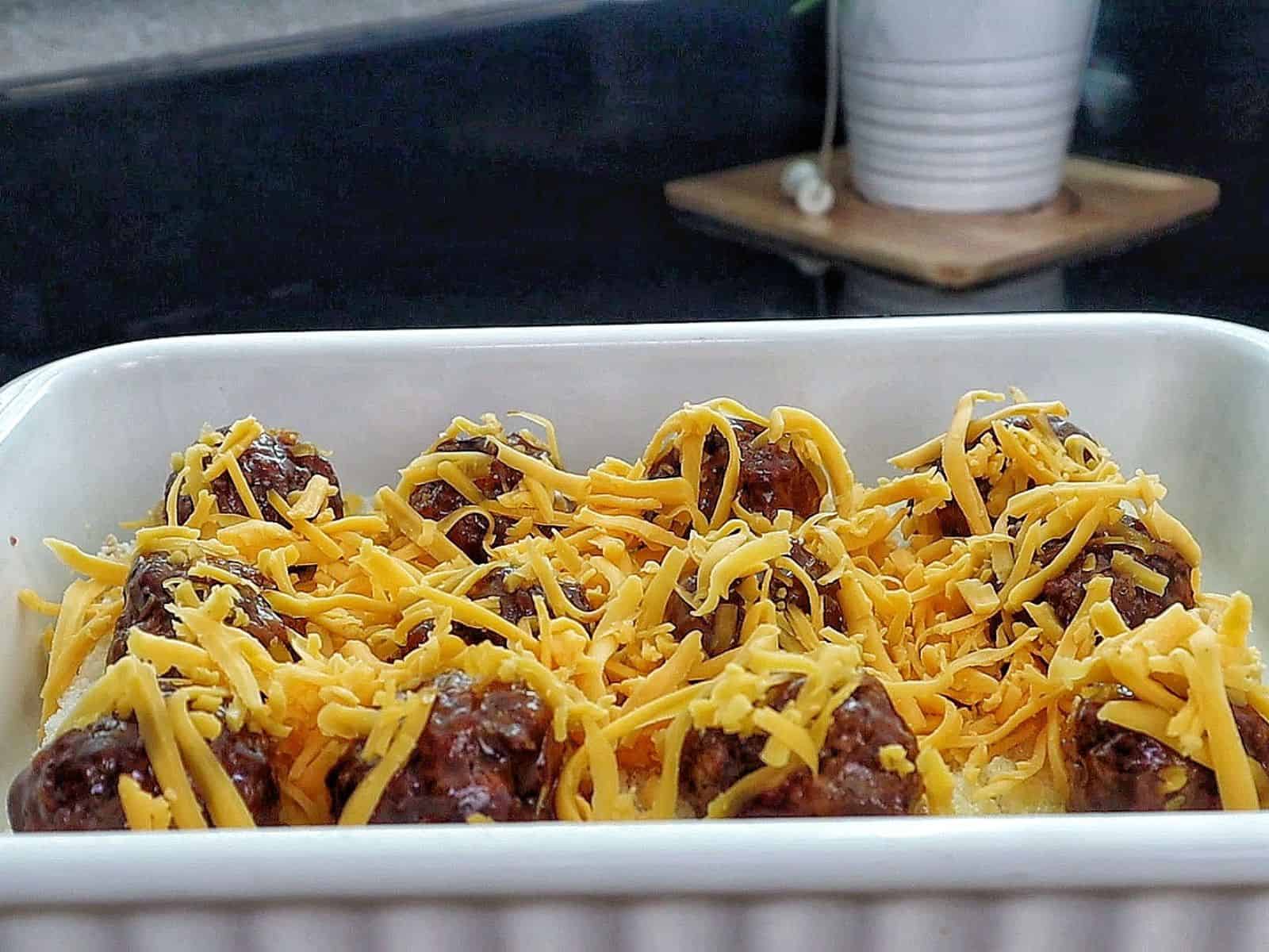 cheesy sweet and spicy BBQ meatball sliders baked inside soft Hawaiian rolls, topped with melted cheddar