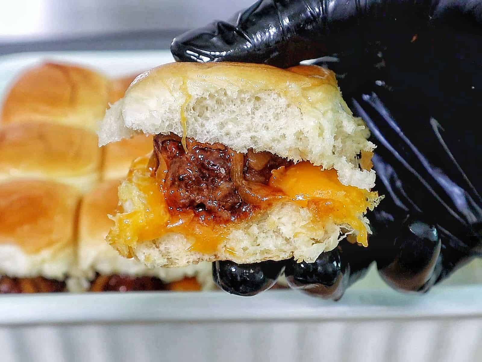 cheesy sweet and spicy BBQ meatball sliders baked inside soft Hawaiian rolls, topped with melted cheddar