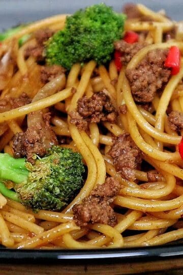 Beef stir-fried noodles with broccoli florets, red chili slices, and onions in a savory sauce.